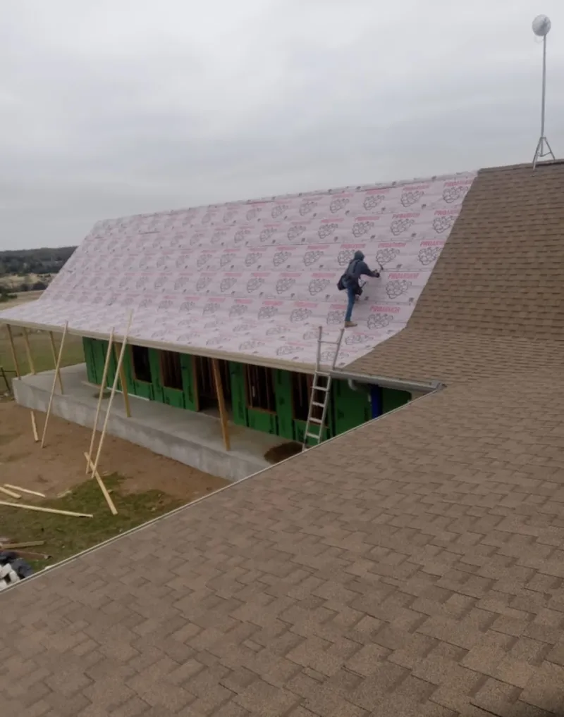 Worker preparing underlayment for a metal roof installation in Lakewood